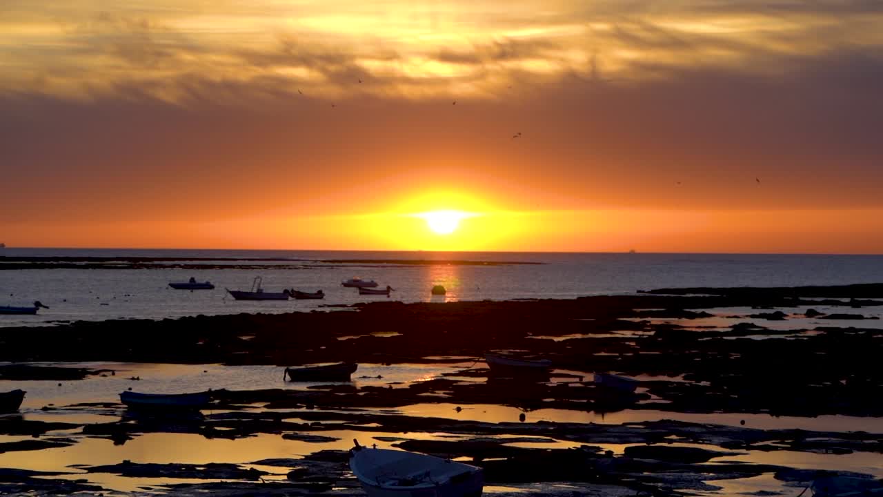 hermosa puesta de sol con silueta de playa y barcos de pesca durante la marea baja