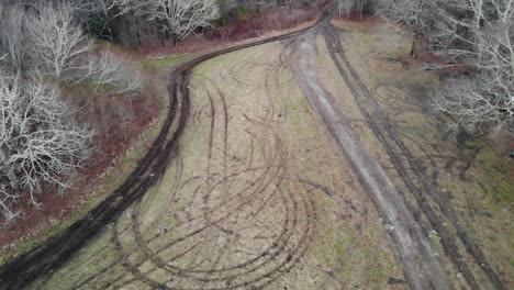 tire tracks in grass field in forest aerial drone tilt descending