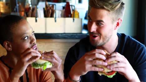 una pareja feliz comiendo una hamburguesa.