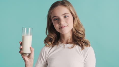 teenage caucasian girl in pijamas holding a glass of milk and smiling.