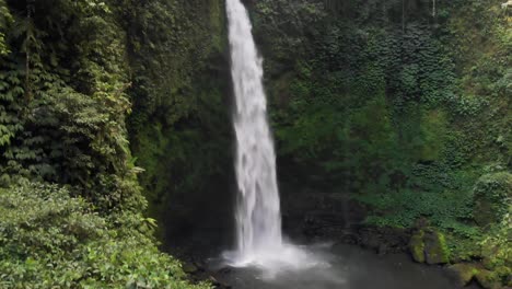 A-drone-captures-the-power-and-magnificence-of-the-Nungnung-Waterfall-as-it-rises-to-the-top-of-the-falls-in-Bali,-Indonesia