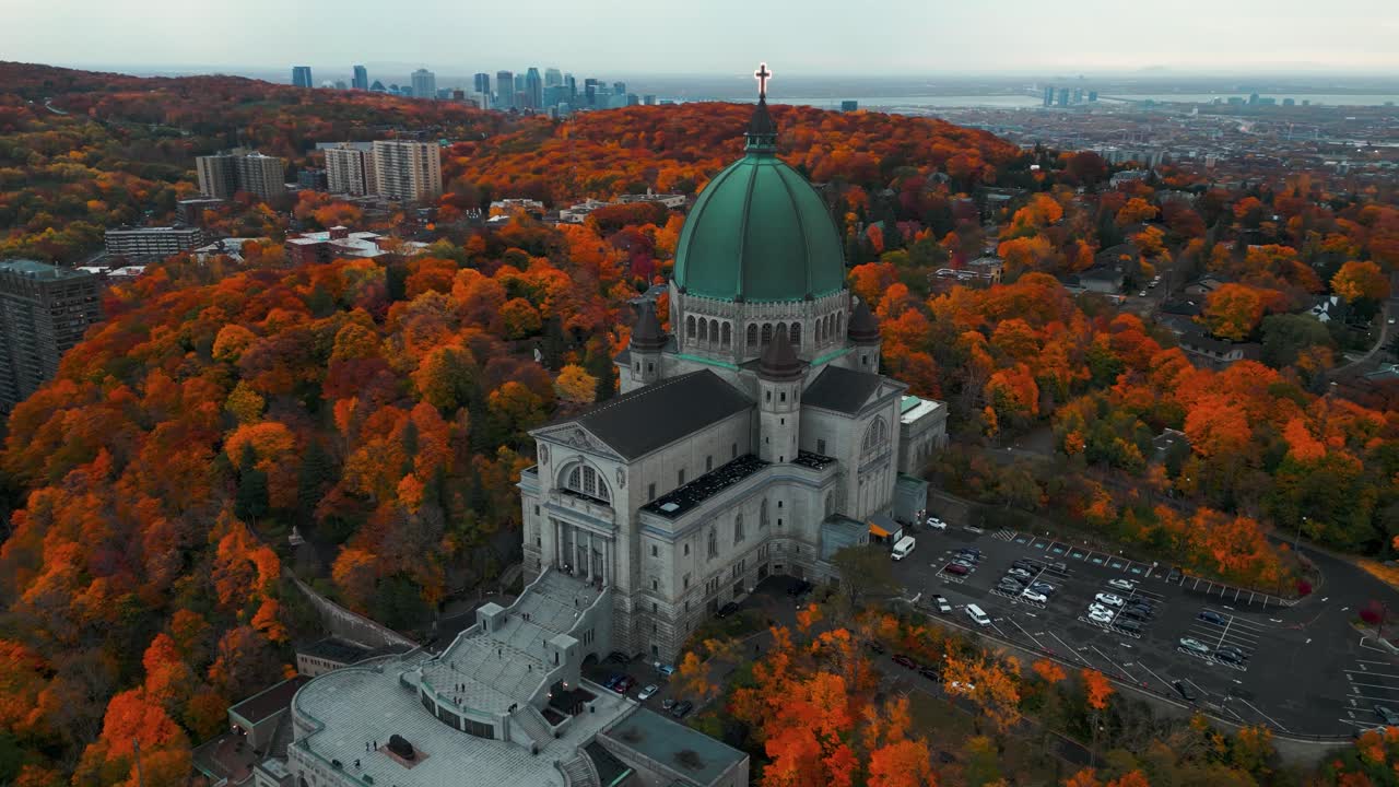 aerial shot around Saint Joseph Oratory in Montreal city with the skyline in the backgound and colorful trees at fall season on an overcast day, Quebec Province, Canada