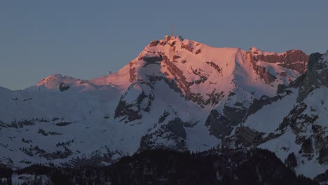 aerial view showcasing the tranquil ambiance of sunrise over a majestic snowy mountain range silhouette, filmed by drone