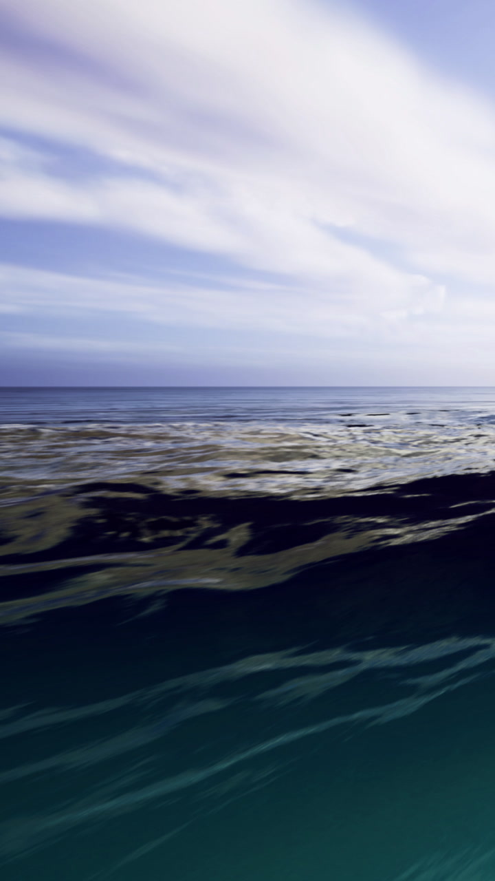 Calm ocean waves gently rolling under a serene blue sky at sunset