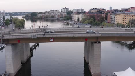 cars, cyclists and pedestrians going over canal on liljeholmsbron bridge in södermalm, stockholm, sweden during cloudy evening