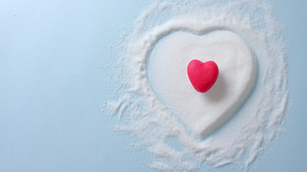 파란색 배경에  ⁇ 은 심장 모양의 설탕 위의 클로즈업, 복사 공간, 슬로우 모션