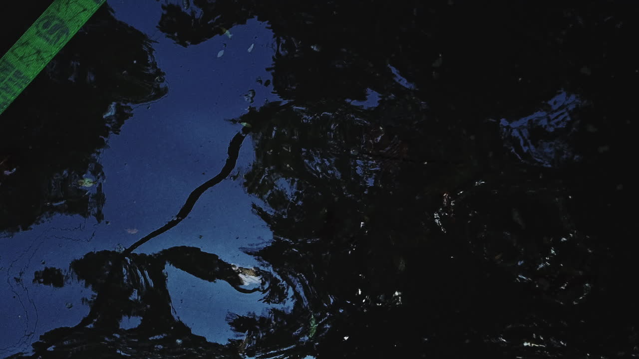 toma aérea a vista de pájaro de un estanque y un reflejo del cielo azul y revela una línea verde floja