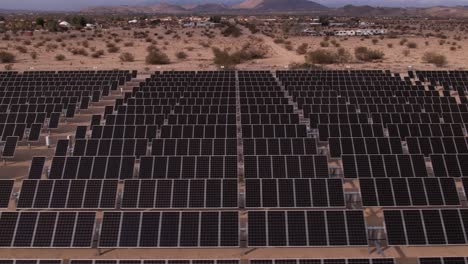 Aerial-Drone-Footage-of-Solar-Panel-Field-in-Joshua-Tree-National-Park-on-a-Sunny-Day-with-rainbow-in-the-background,-vertical-tilt-and-zoom-out