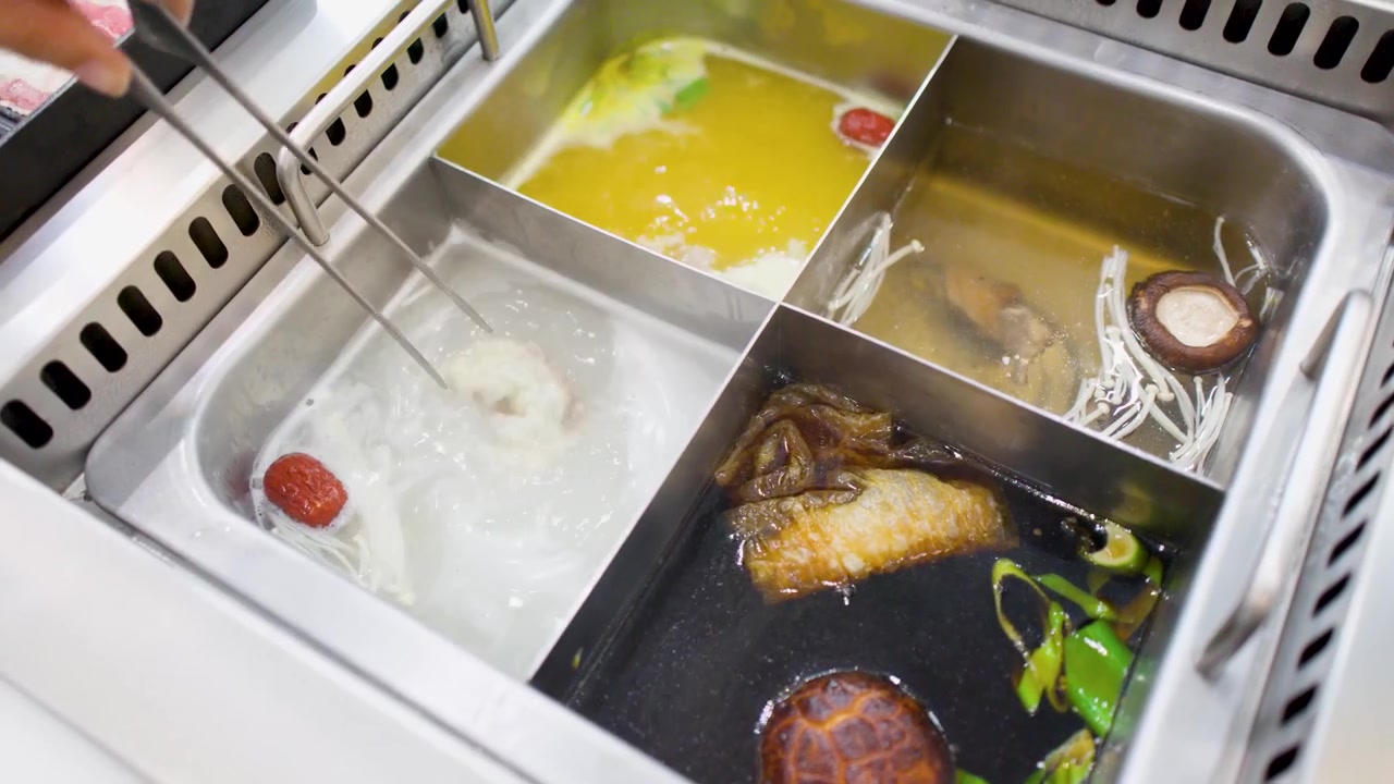 Cottura di ingredienti freschi in una pentola hot pot a più scomparti con brodi diversi