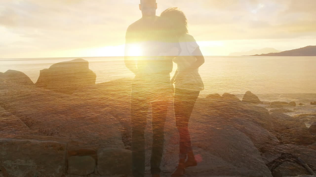 Embracing couple on rocky shore during sunset with ocean animation background