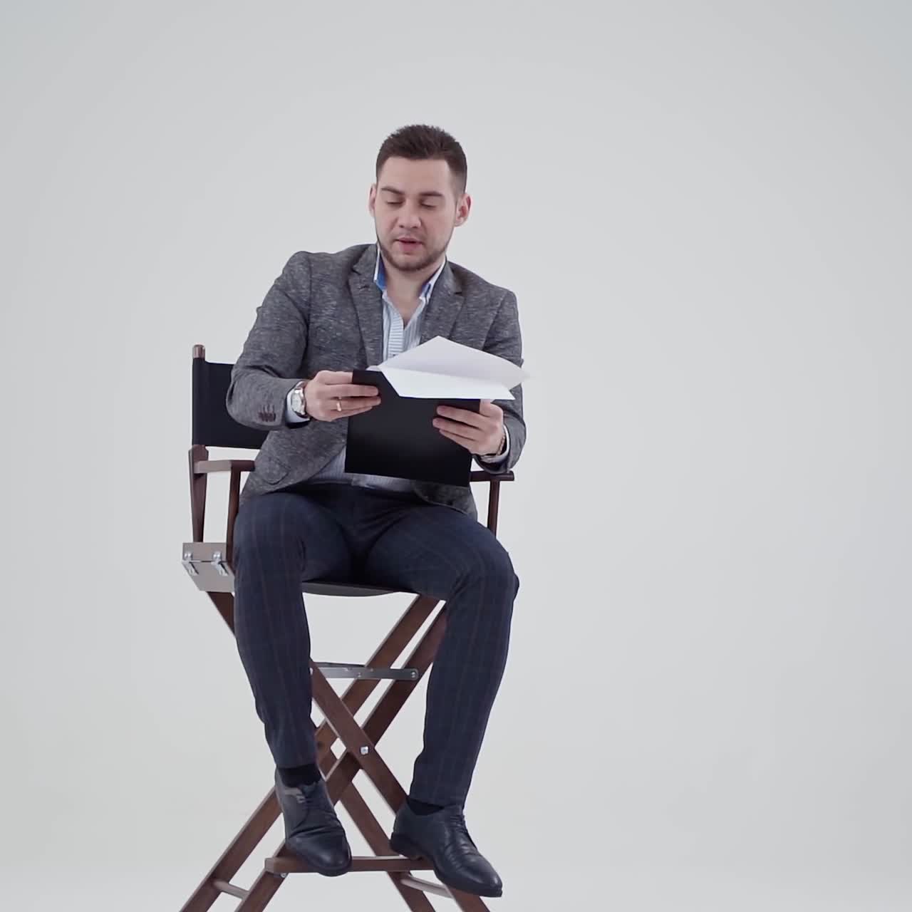 Businessman in a chair shouting. Many papers are flying in the studio and a man in suit with opened mouth. Slow motion.