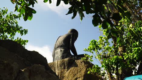 Statue-of-a-lonely-man-sitting-on-a-rock,-waiting