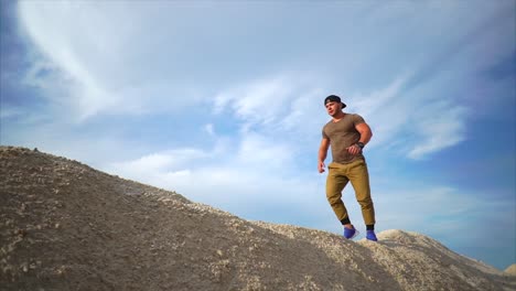 man walking on hill under a cloudy sky