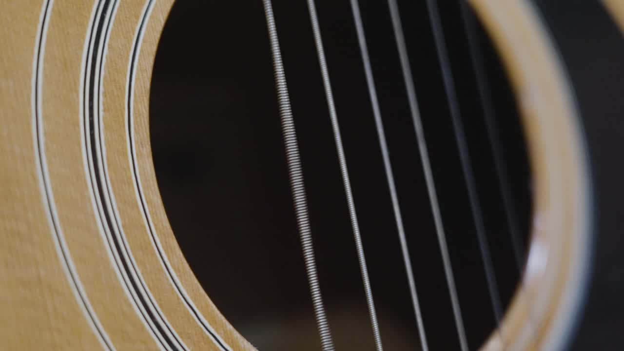 Extreme slo mo clip over the sound hole of an old acoustic