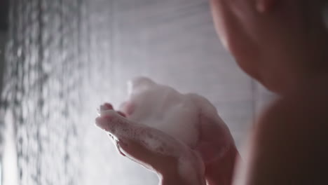 woman plays with foam in shower cabin closeup. playful lady blows heavy soap froth washing body in bathroom. having fun during bathing procedures