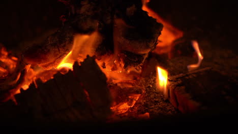 night shot of red hot bonfire flames burning from glowing red coals with a few small sparks flying out of the fire