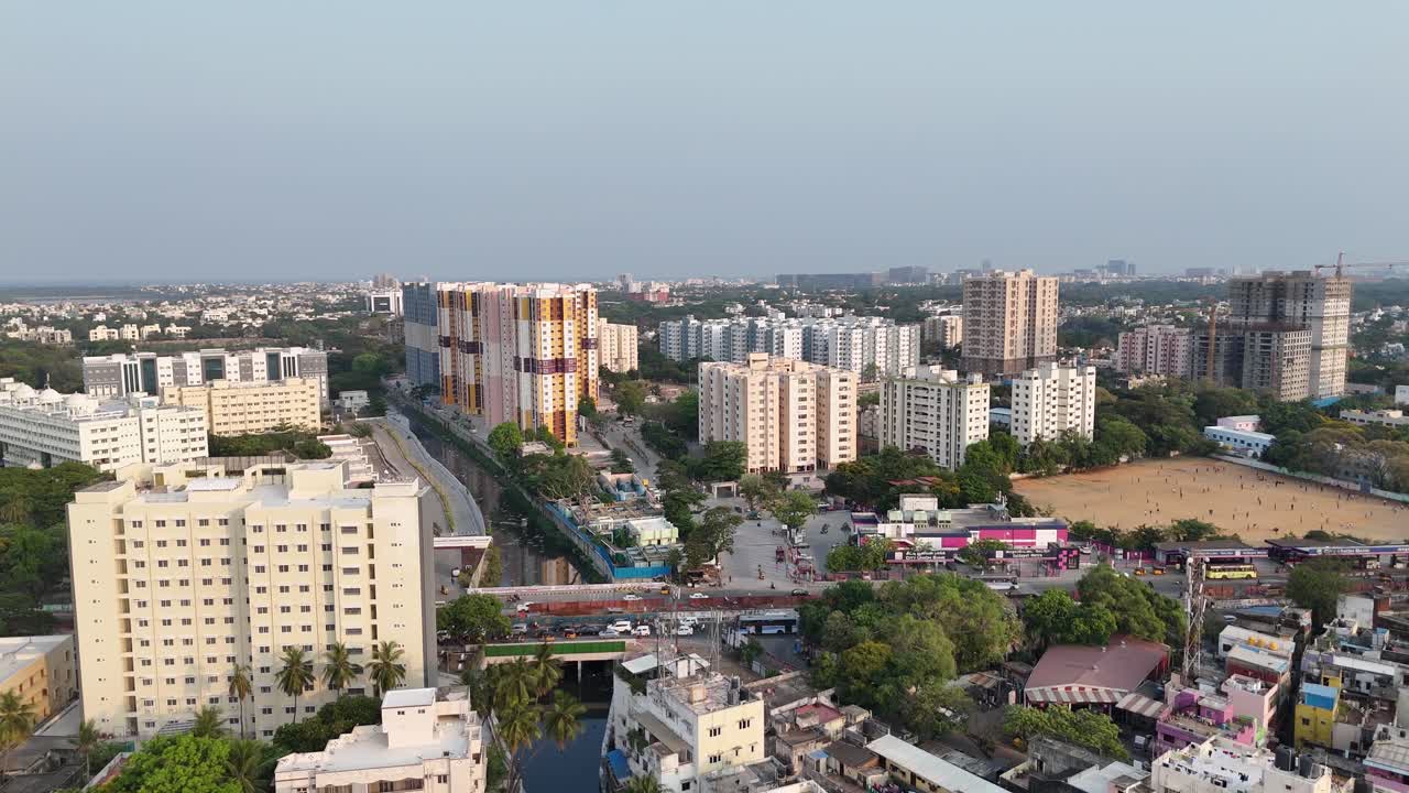 Vista aerea di Saidapet circondata da altri complessi di appartamenti e strutture commerciali. In primo piano si vedono i tetti di edifici più piccoli e densamente affollati. È visibile un cavalcavia.