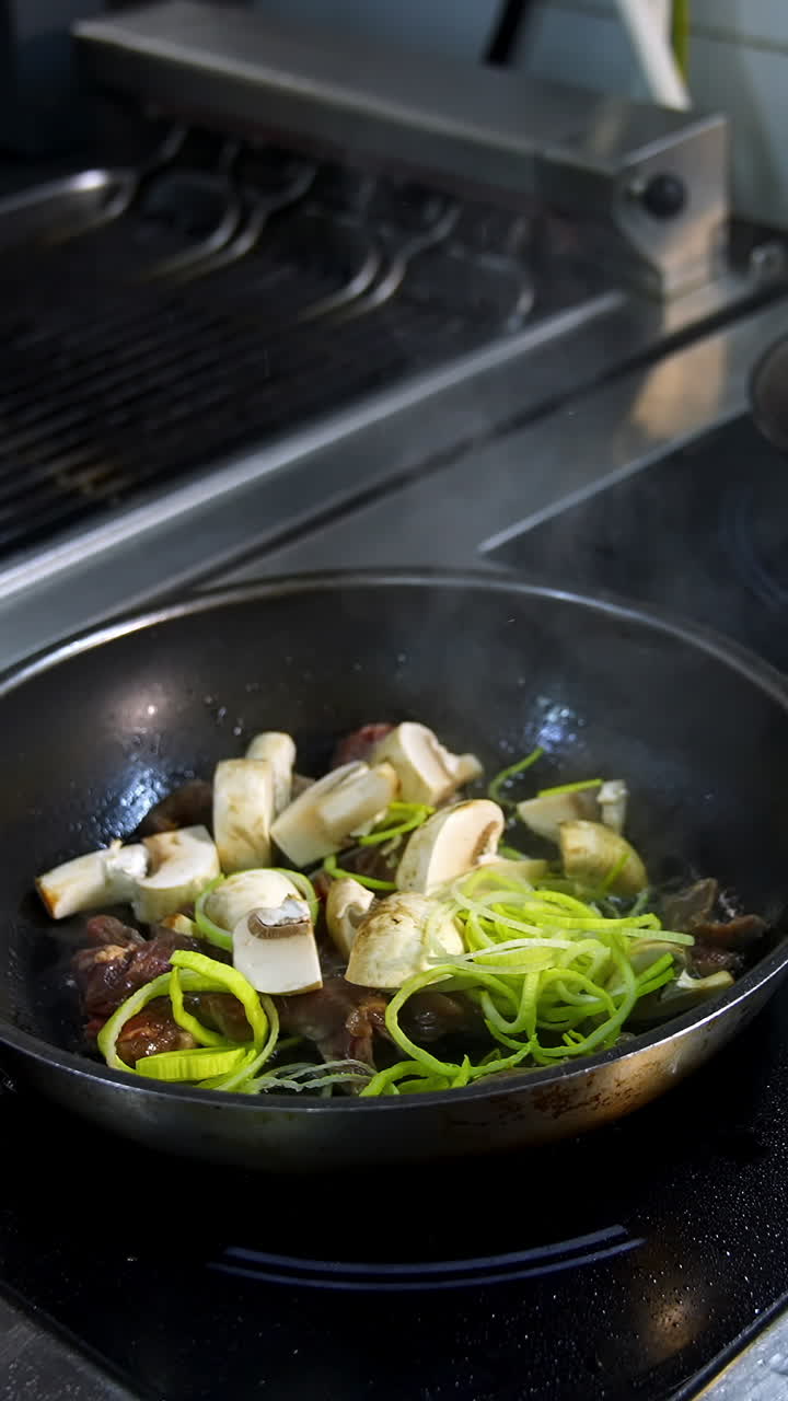 Cooking food in frying pans. Chef pouring sauce into the frying mushrooms. Making fried mixed vegetable with sauce in metal pan in the restaurant kitchen. Vertical video