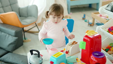 adorable little girl playing with toy plastic kitchen tools at home