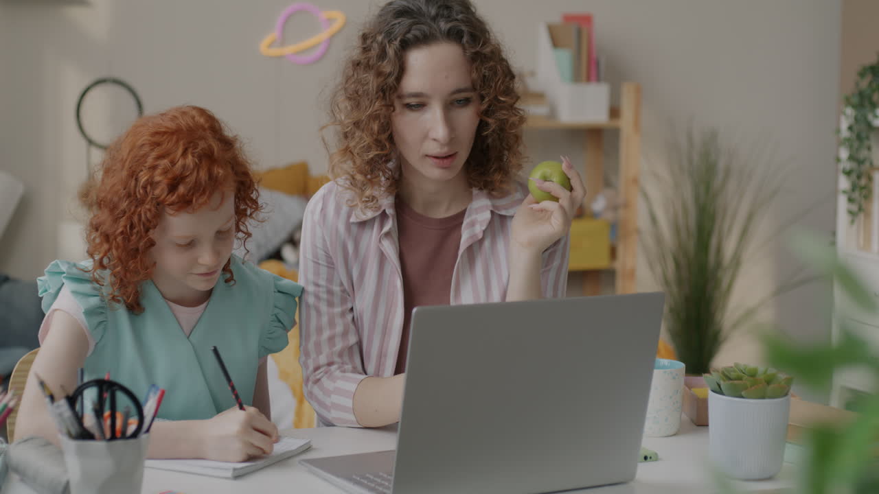 Mother helping daughter with online schoolwork