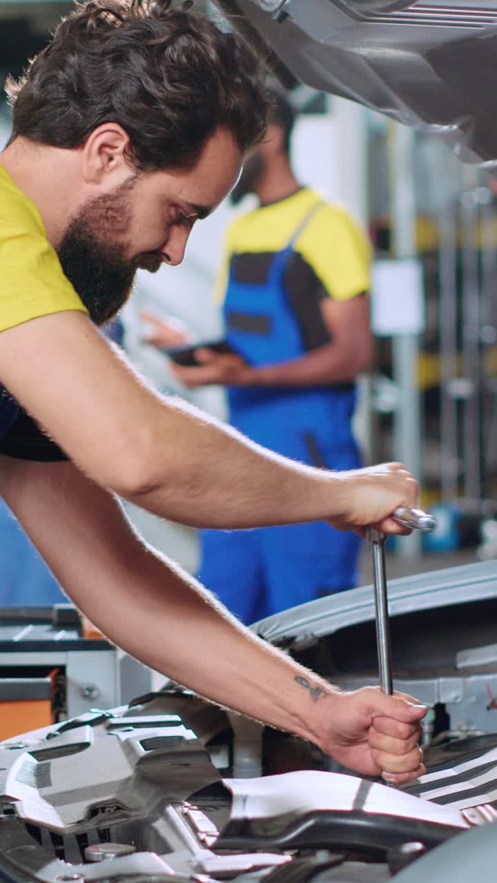 Vertical video Serviceman in car service uses wrench