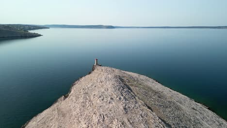 layers of rock from above with light beacon at far end point, deep blue adriatic sea and coastline