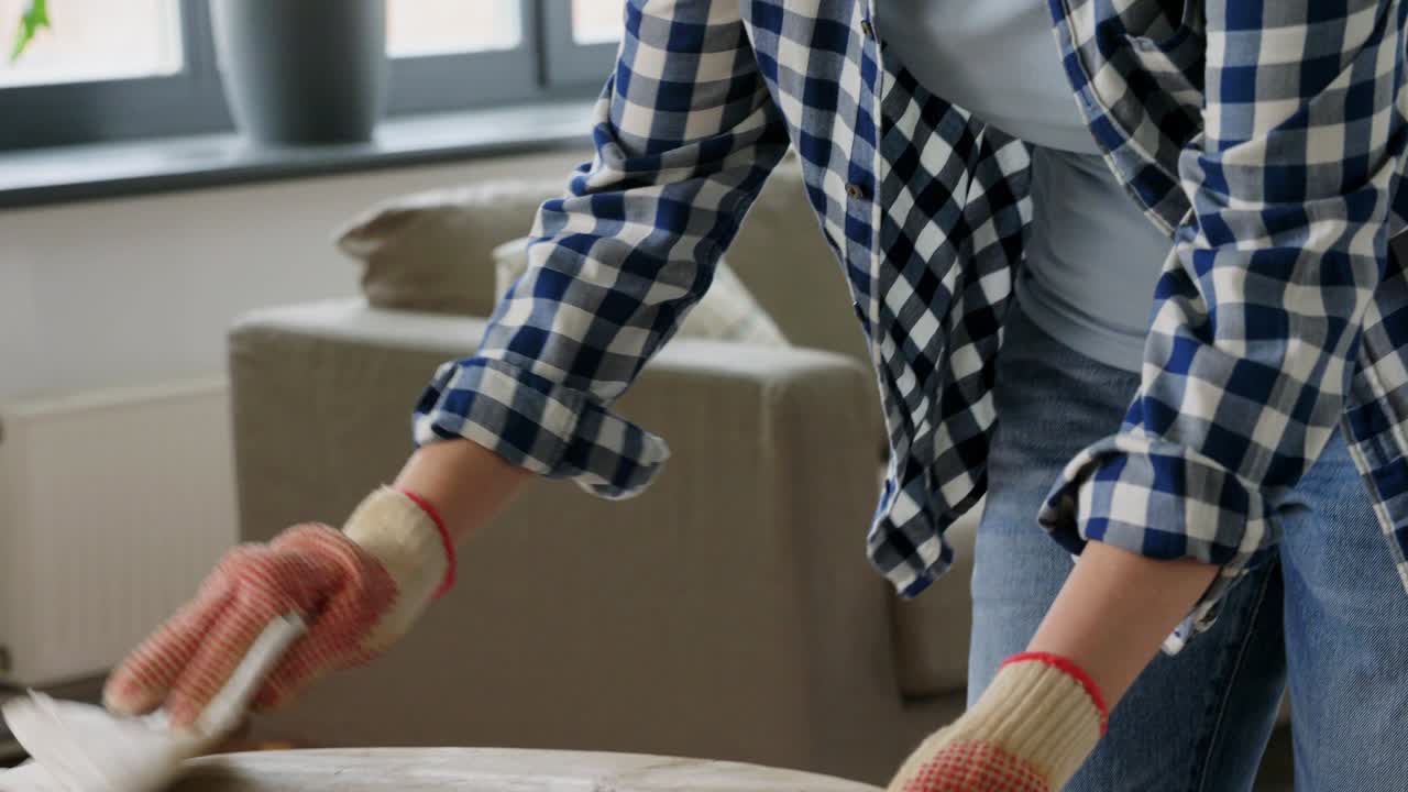 mujer desengrasando la superficie de la mesa vieja con disolvente