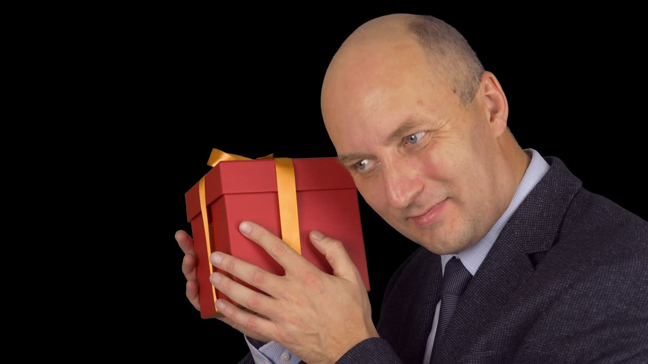 행복한 코카시안 사업가 선물. 금색 노란색 활과 함께 빨간 선물 상자. 남자 체크 선물 상자를 흔들고. 가까이에 잠겼습니다. 알파 채널 크로마 키 투명한 배경.