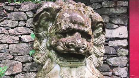 a grungy chinese guardian lion foo dog sculpture at the park - close up