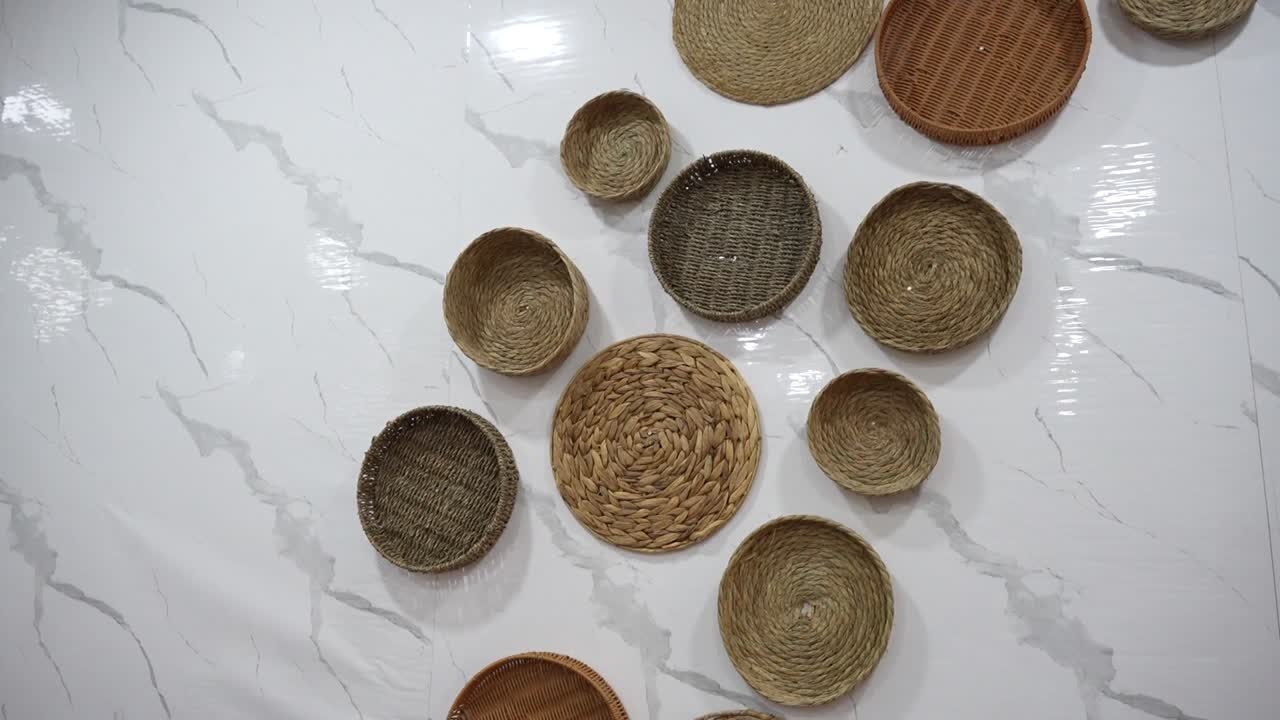 Assorted traditional woven baskets arranged on a white textured restaurant wall. Pakistan