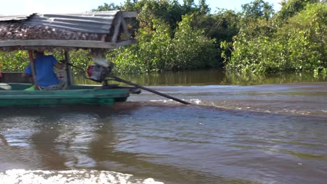 indigenous wooden boat crossing on jungle river in amazon rainforest on sunny day