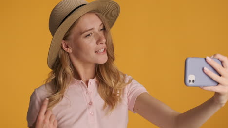 mujer caucásica con un sombrero haciendo una llamada de video en el teléfono inteligente.