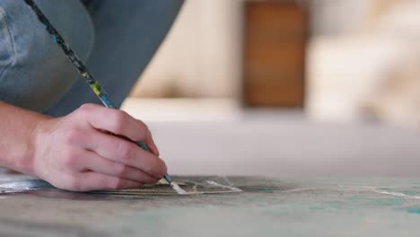 Hombre-Blanco-Pintando-Obras-De-Arte-En-El-Suelo-Usando-Un-Pincel,-De-Cerca