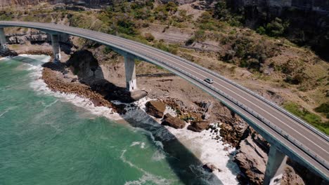 car drives at sea cliff bridge on sunny day in sydney, nsw, australia