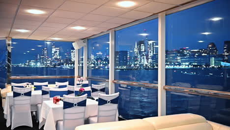 empty tables at the restaurant on the board of the riverboat. view on the night scenery of new york in the windows