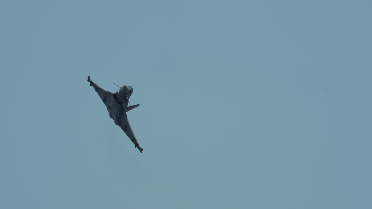 Jet aircraft flying overhead with visible undercarriage and decorated tail wings during flight