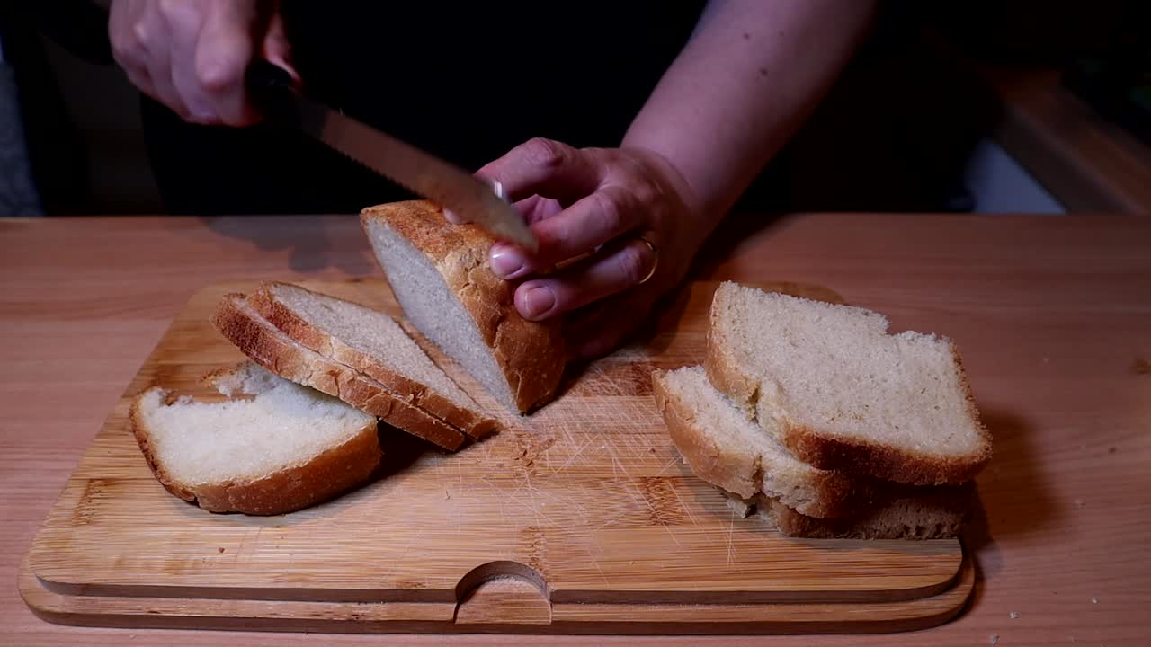 Cutting homemade bread with a knife on wooden table