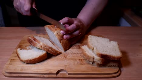 cortar pan casero con un cuchillo sobre una mesa de madera