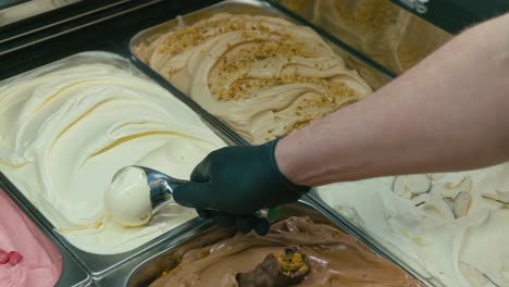 sacando un helado de gelato de un escaparate en una heladería