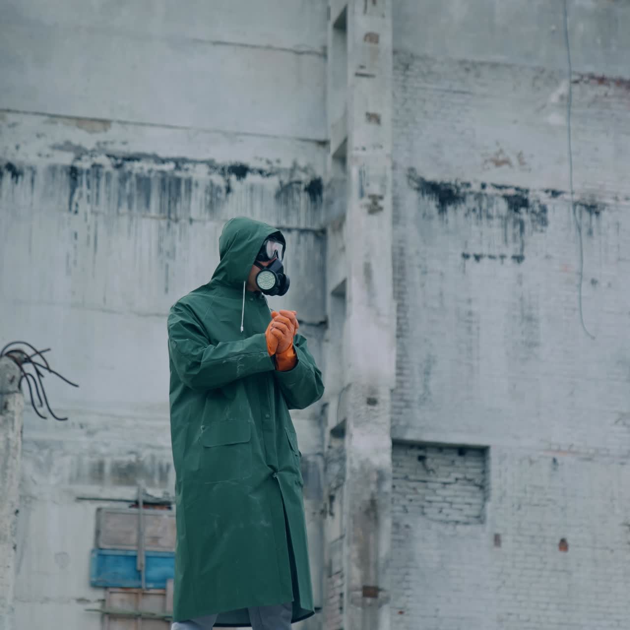 Human in respirator looking at the ruined building and preparing to the work. Ecologist in the abandoned place after biological attack concept