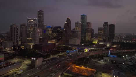 Trucking-backwards-and-pedestaling-down-drone-shot-of-the-Houston-skyline-at-night