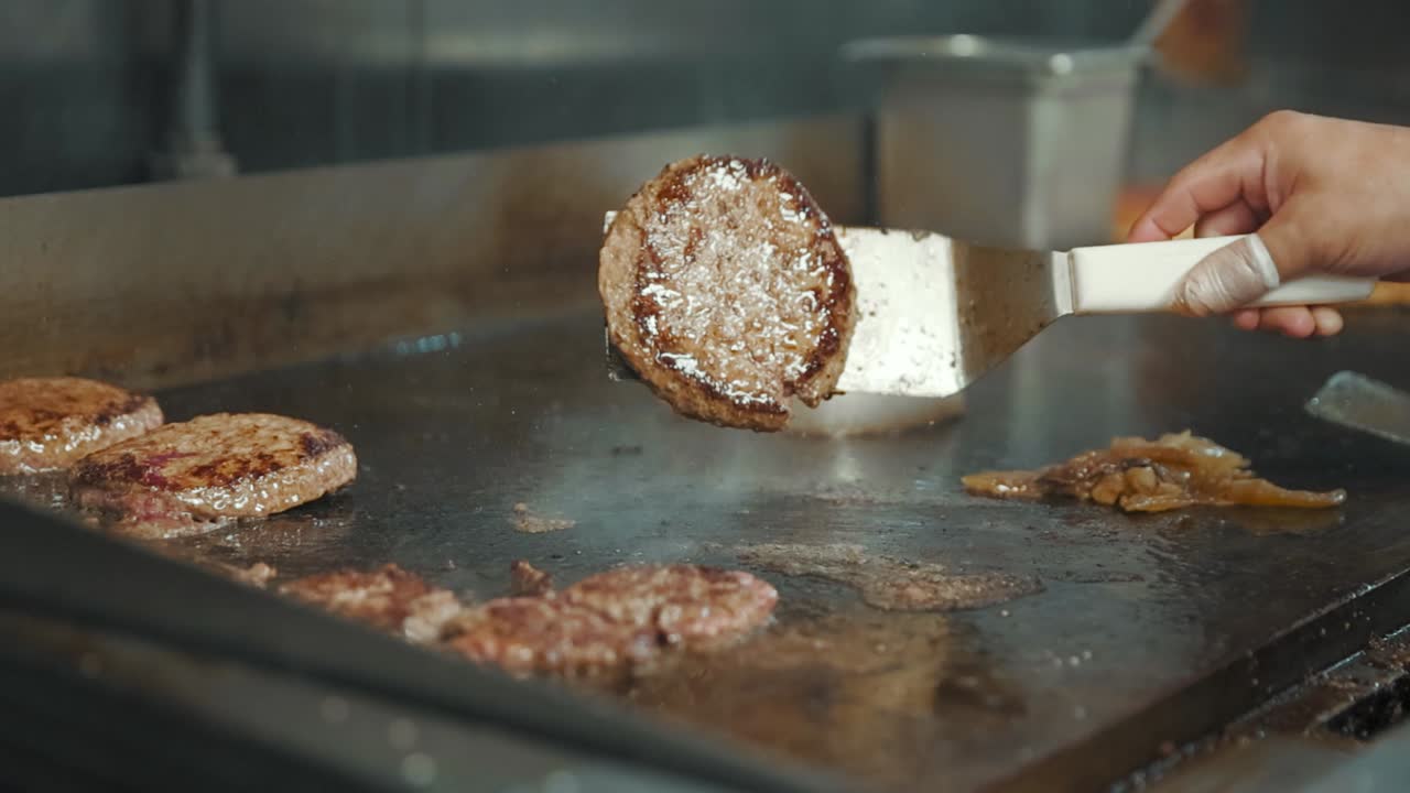 A juice burger patty being flipped on a hot grill