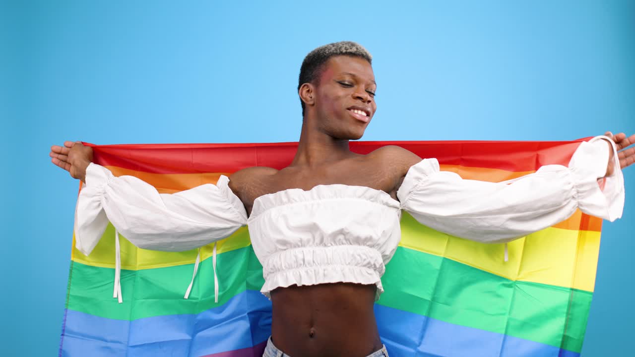 Selvsikker person vifter med LGBTQ+-regnbueflag i studie