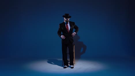 a man in a suit and fedora smoking a cigar under a spotlight