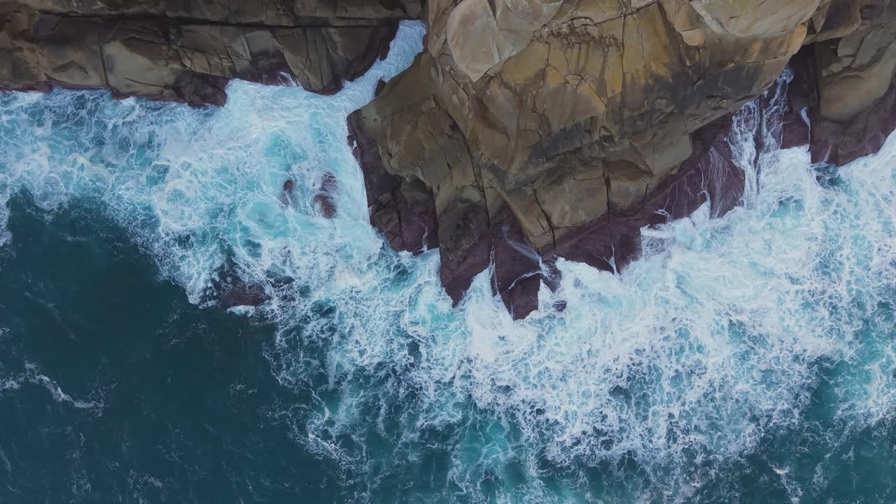Onde impetuose che si infrangono sulle scogliere verticali di Cantís de Papel vicino a Xove, nella provincia di Lugo, in Galizia, Spagna. Ripresa aerea dall'alto verso il basso