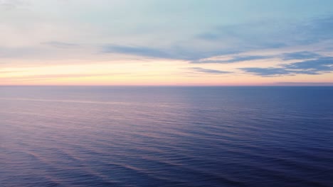 Endless-calm-ocean-horizon-during-vibrant-sunset,-aerial-drone-view