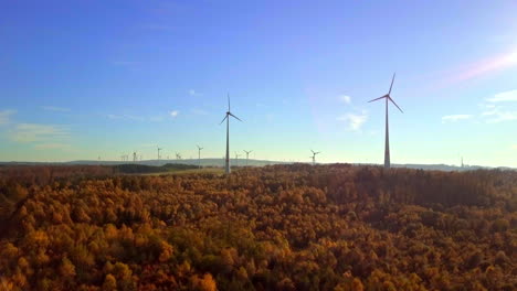 la cámara vuela lentamente sobre un bosque otoñal con vistas a molinillos majestuosos entre los árboles, filmada en 4k