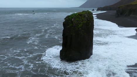 las olas espumosas que se estrellan en el mar en la playa de arena negra de laekjavik en islandia