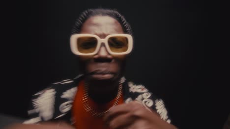 black hip-hop musician in sunglasses and stylish outfit rapping on camera