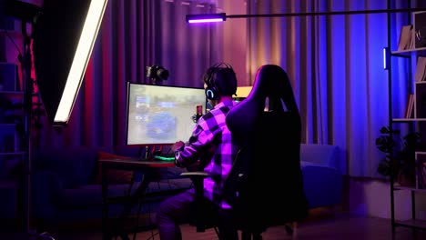 rücksicht auf einen asiatischen streamer-jungen, der ein rennspiel über das netzwerk auf einem pc spielt. gähnen und schlafen, live-stream-videospiel, schreibtisch mit rgb-lead-strip-licht beleuchtet
